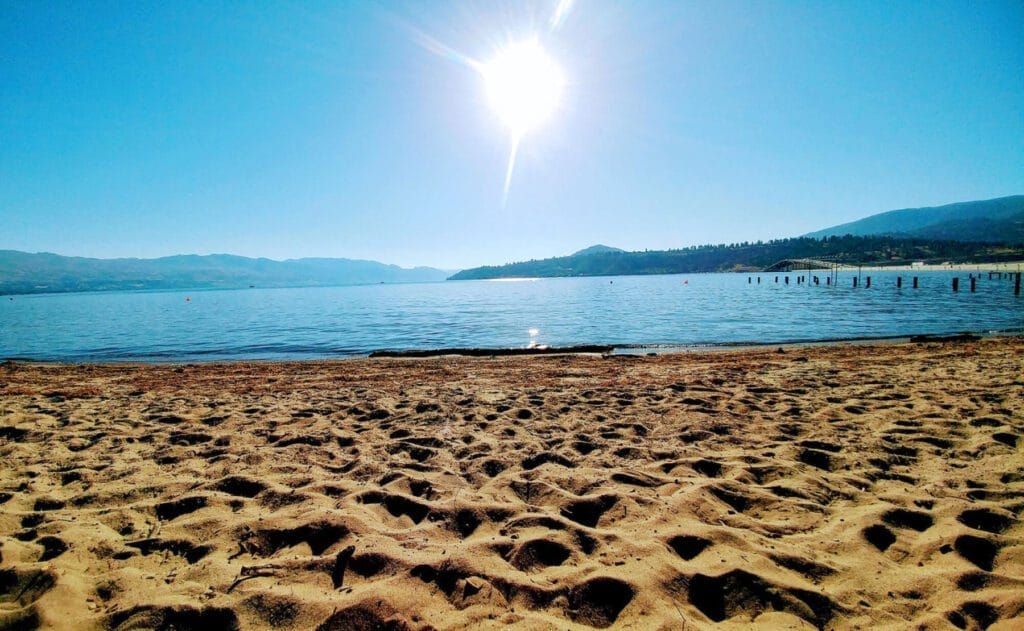 A serene sandy beach with majestic mountains rising in the background, creating a stunning natural landscape.