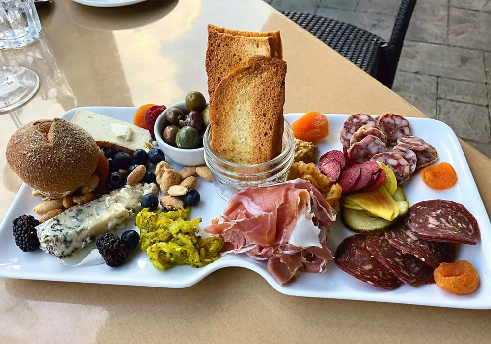 A delicious spread on a table, including bread, cheese, meats, and fruits, perfect for sharing and enjoying.