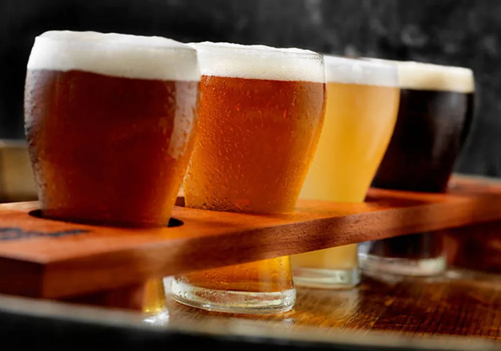 A wooden tray displays several beer glasses, each filled with different brews, ready for tasting.