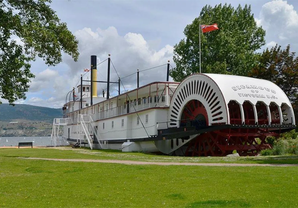 The historic SS Sicamous paddle wheel boat is parked on the grass, inviting visitors to explore Okanagan's maritime heritage.