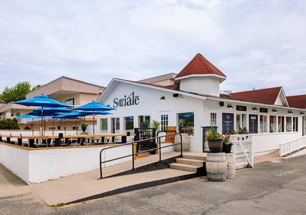The front of Socialē, a local restaurant adorned with bright blue umbrellas, creating a welcoming atmosphere for outdoor diners.