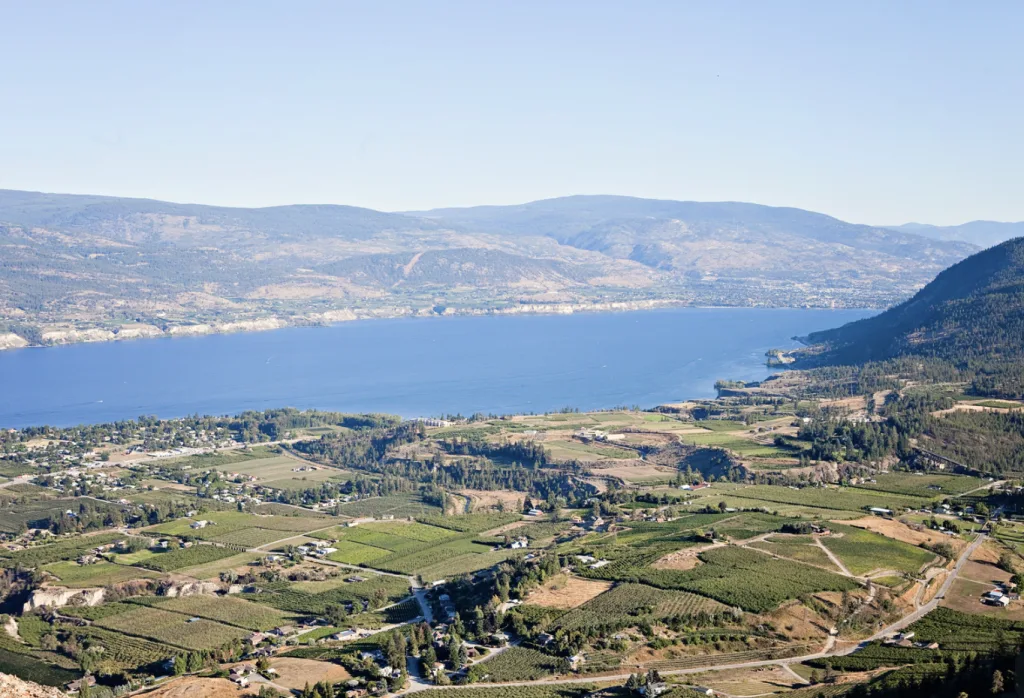 A breathtaking view of a serene lake surrounded by majestic mountains, captured from a picturesque hilltop.